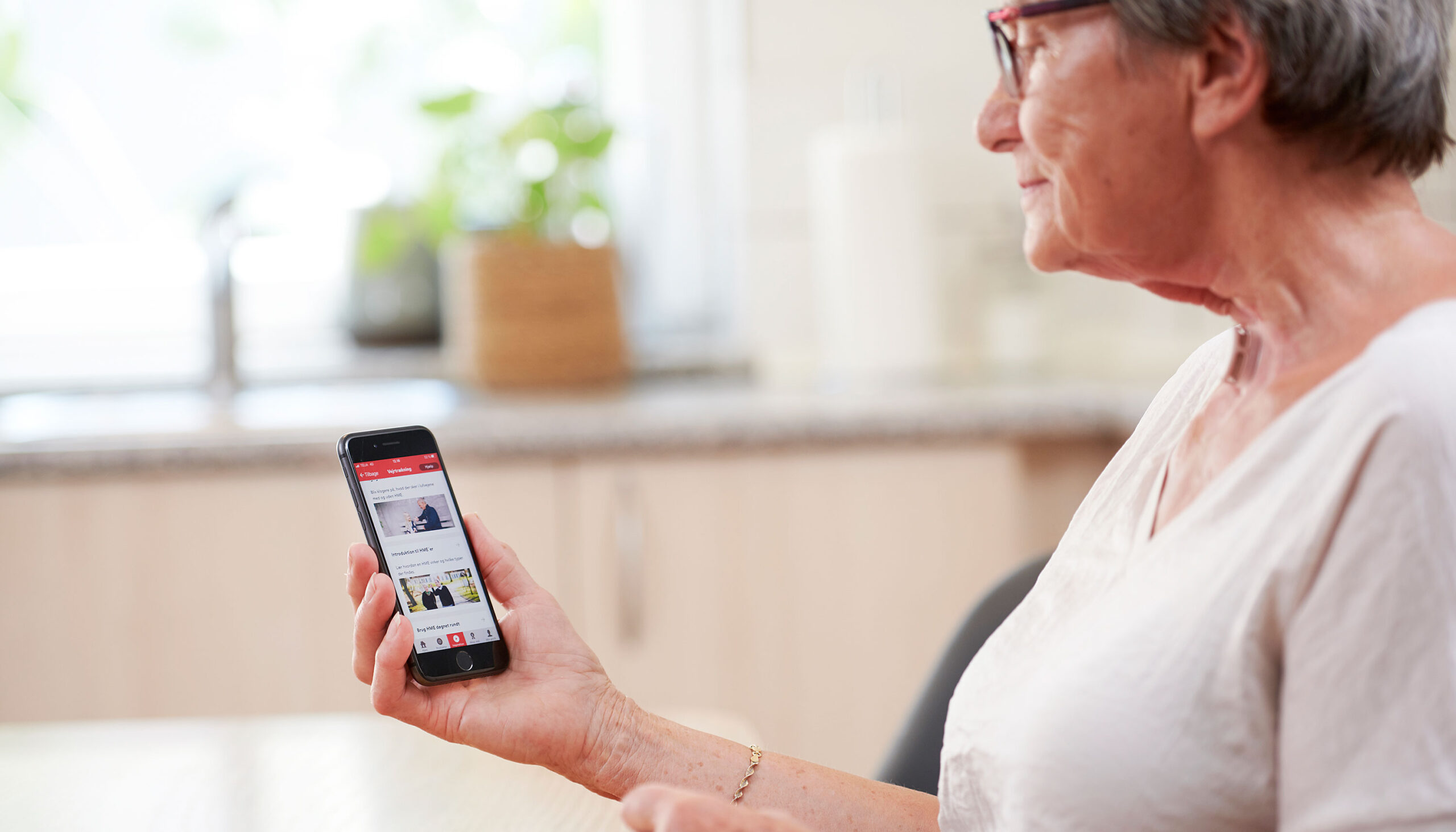 Lady with a neck stoma is looking at her phone.